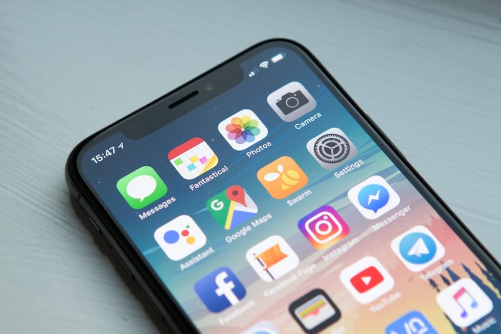 Hand typing on a sleek smartphone screen with a contacts list visible in soft focus background